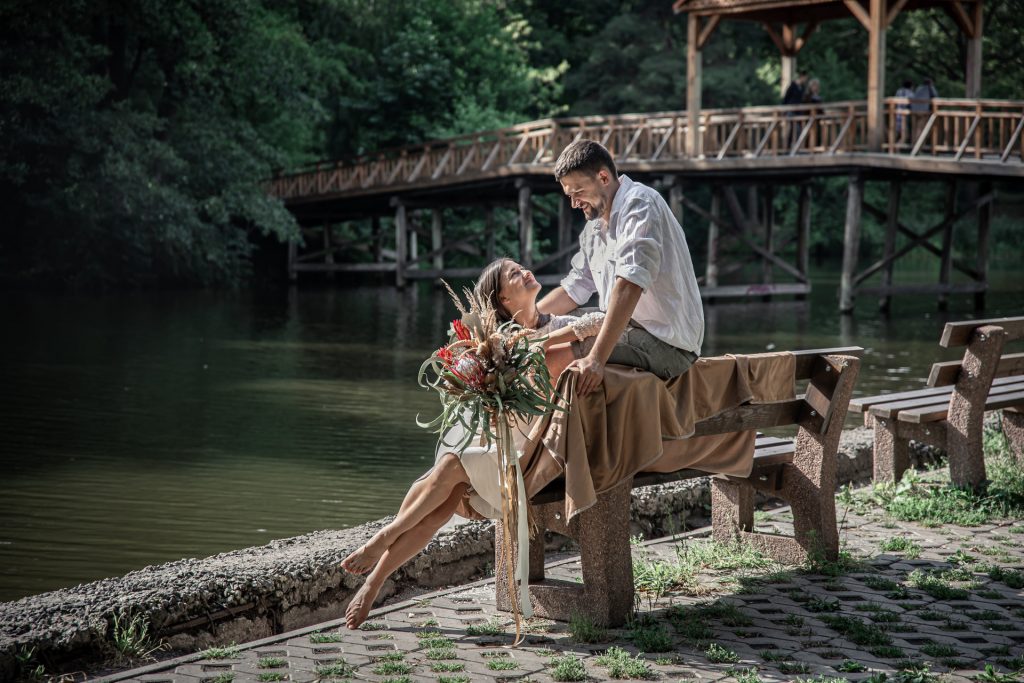 beautiful-young-woman-with-flowers-her-husband-are-sitting-bench-enjoying-communication-date-nature-romance-marriage (1)