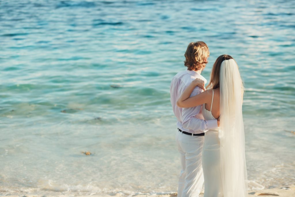 Wedding couple watches the sea standing on the beach