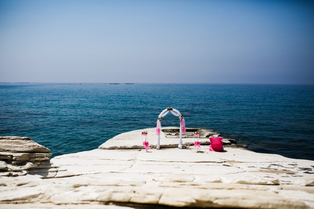 Pink wedding altar stands on the stones before a sea